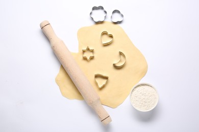 Raw dough, wooden rolling pin, flour and cookie cutters isolated on white, top view