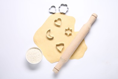 Raw dough, wooden rolling pin, flour and cookie cutters isolated on white, top view