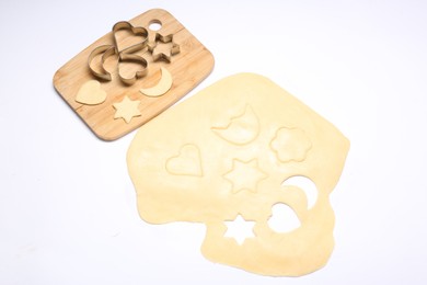 Photo of Raw dough, wooden board and cookie cutters isolated on white, above view