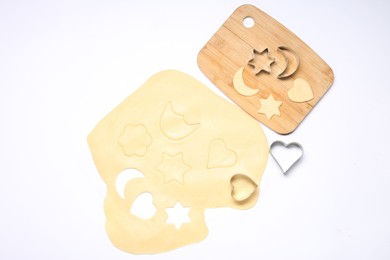 Photo of Raw dough, wooden board and cookie cutters isolated on white, top view