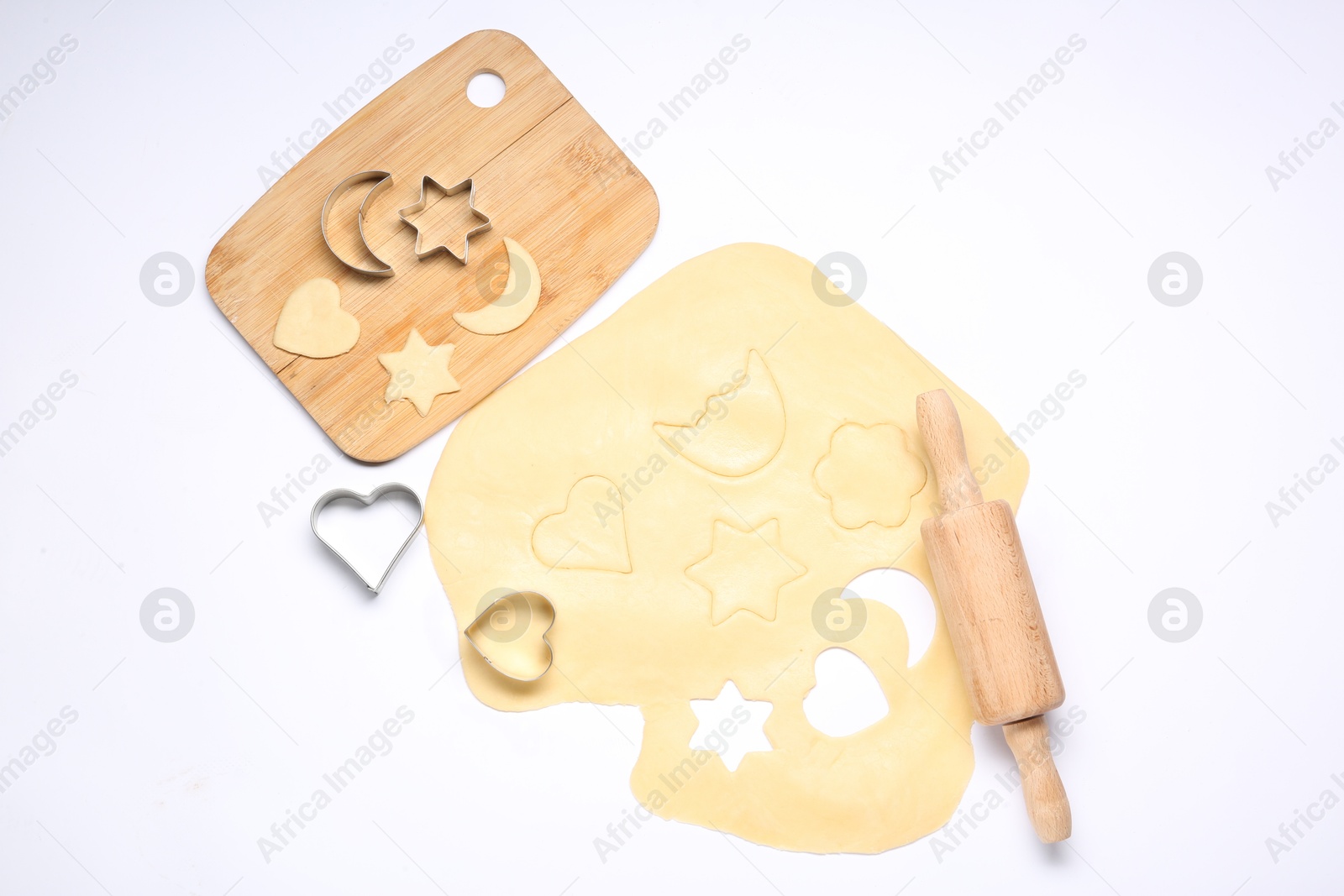 Photo of Raw dough, wooden rolling pin, board and cookie cutters isolated on white, top view