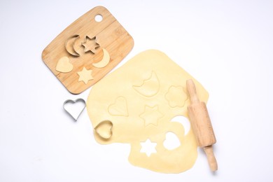 Photo of Raw dough, wooden rolling pin, board and cookie cutters isolated on white, top view