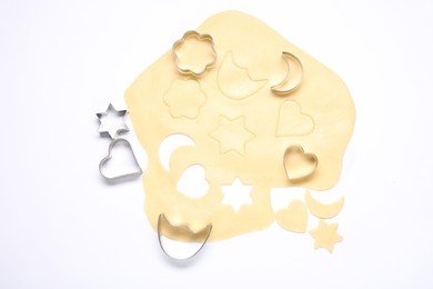 Photo of Raw dough and cookie cutters isolated on white, top view