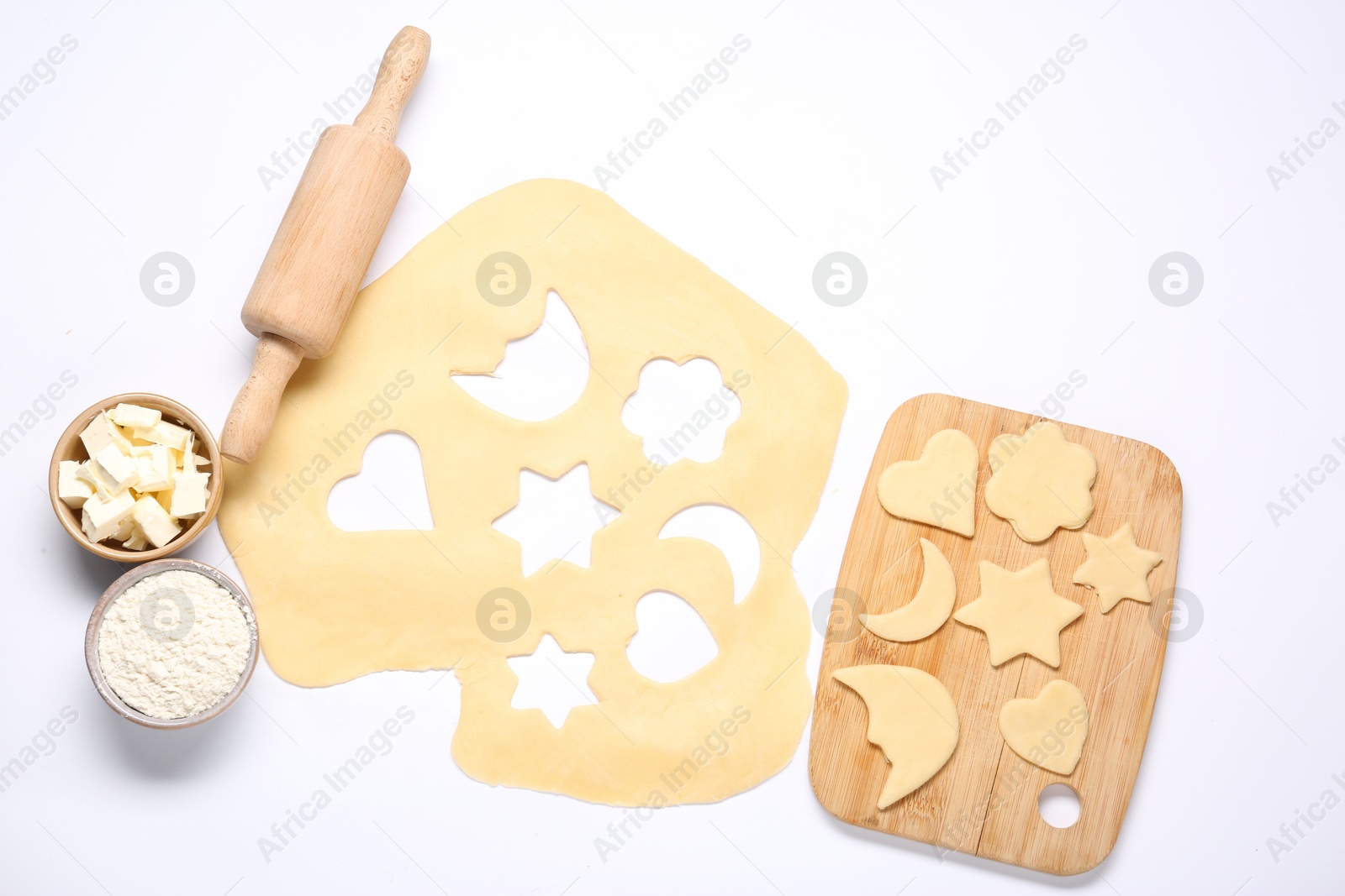 Photo of Raw dough, uncooked cookies, flour, butter, rolling pin and board isolated on white, top view