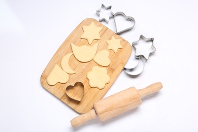 Raw dough, wooden rolling pin and cookie cutters isolated on white, top view