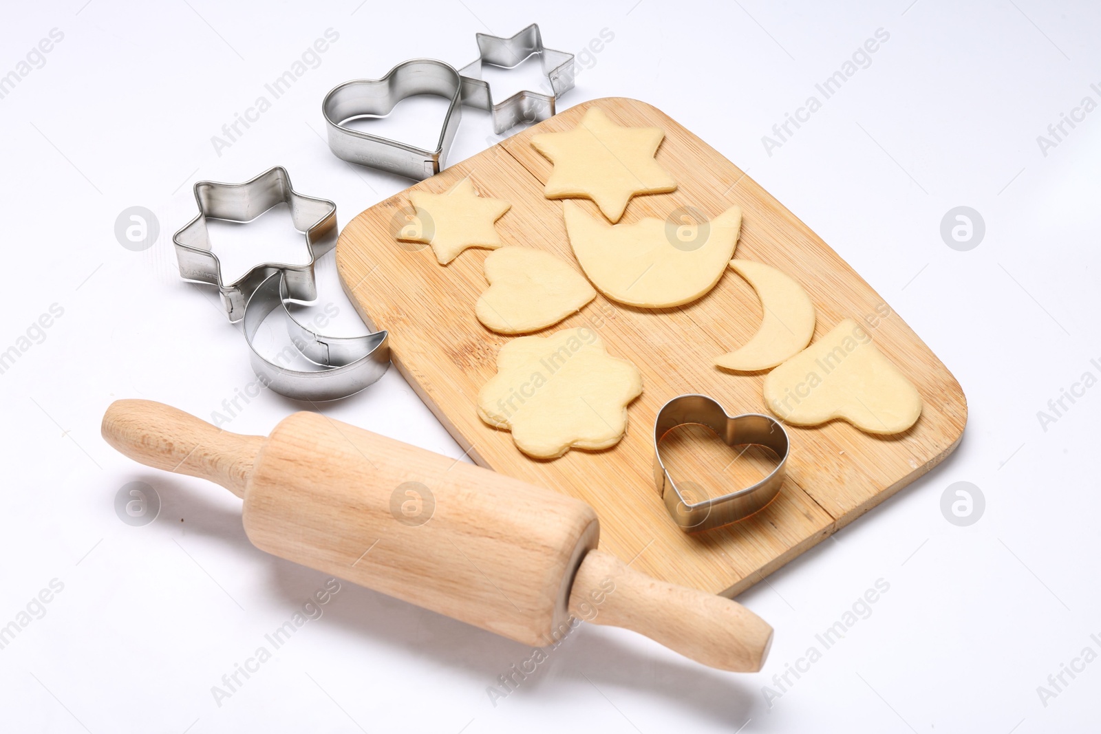 Photo of Raw dough, wooden rolling pin and cookie cutters isolated on white