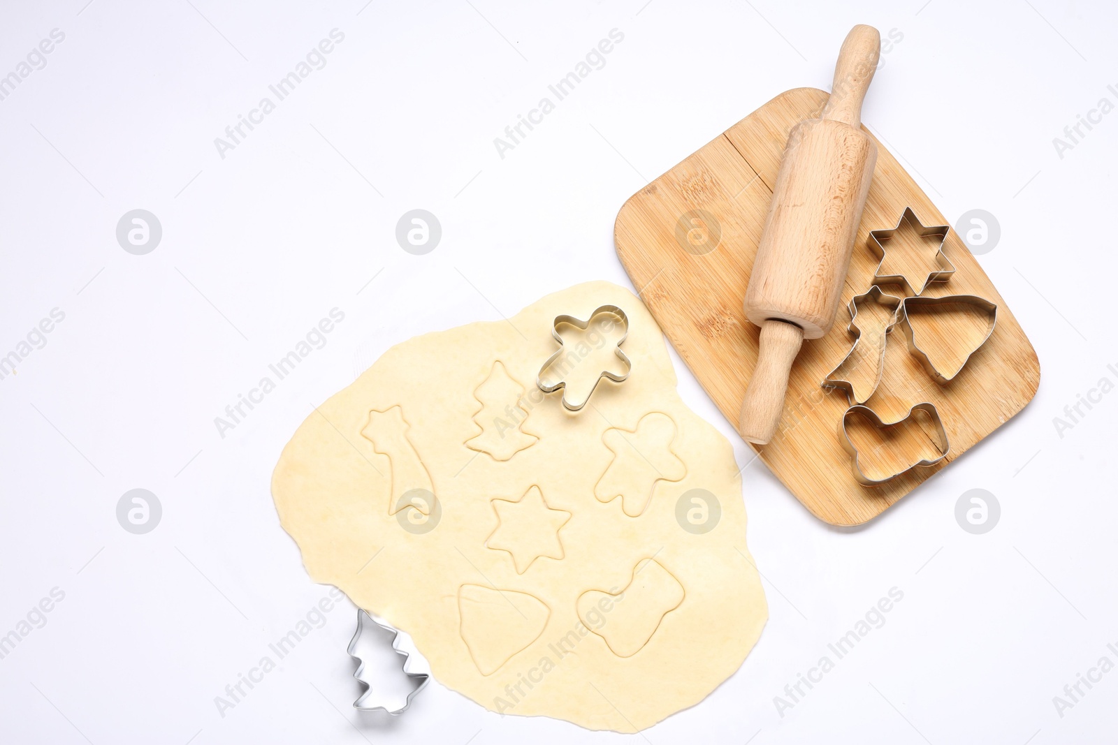 Photo of Raw dough, rolling pin, cookie cutters and board isolated on white, top view