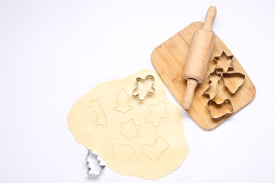 Raw dough, rolling pin, cookie cutters and board isolated on white, top view