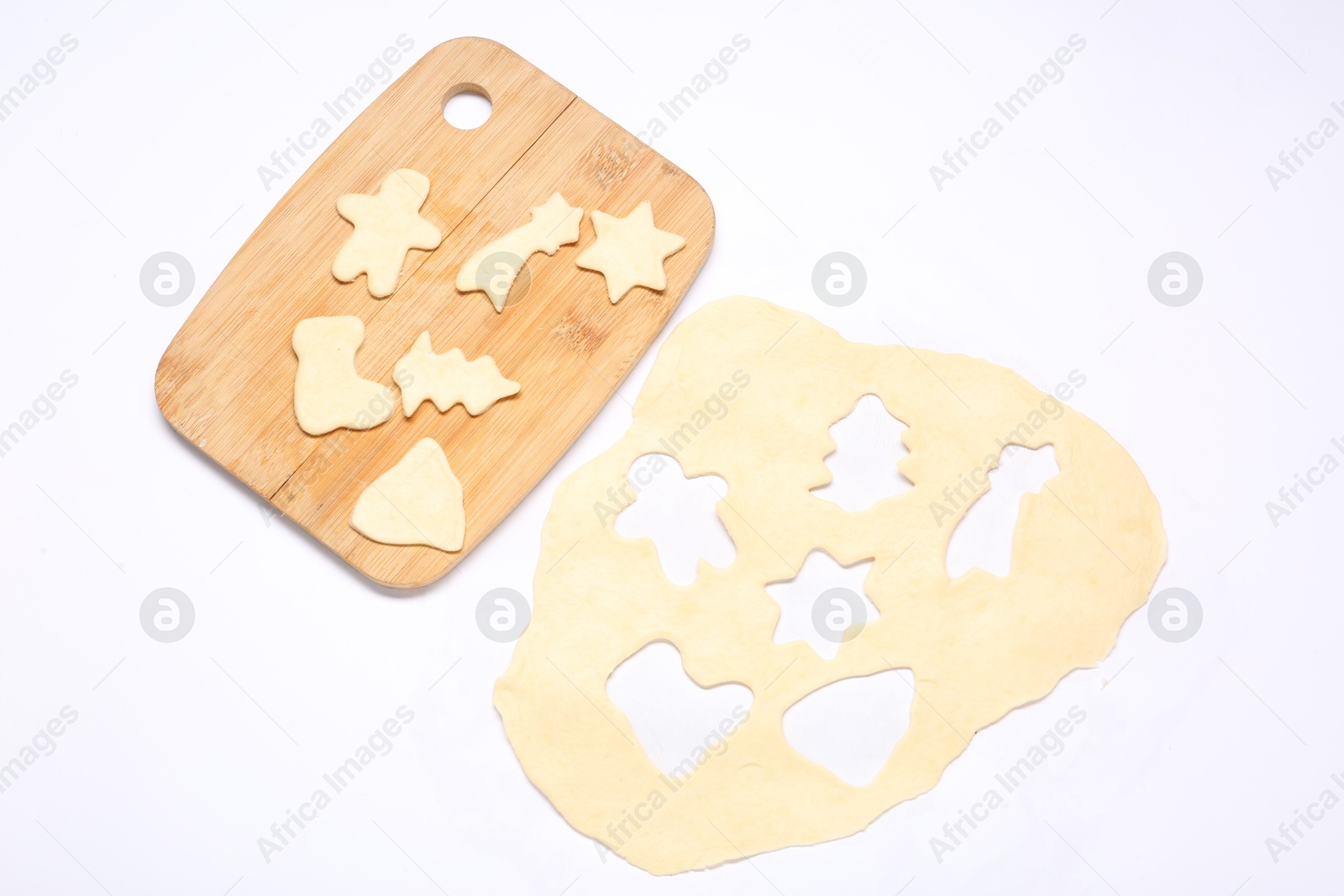 Photo of Raw dough, uncooked cookies and wooden board isolated on white, top view