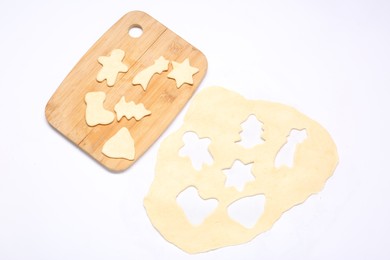 Raw dough, uncooked cookies and wooden board isolated on white, top view