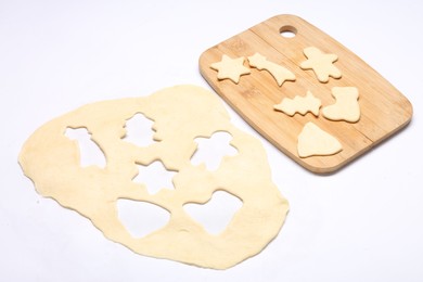 Raw dough, uncooked cookies and wooden board isolated on white