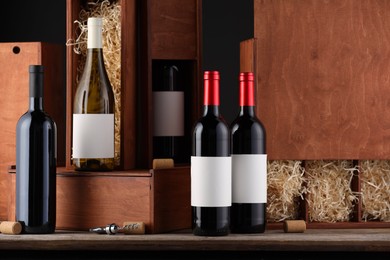 Photo of Different bottles of wine, wooden boxes, corks and corkscrew on table