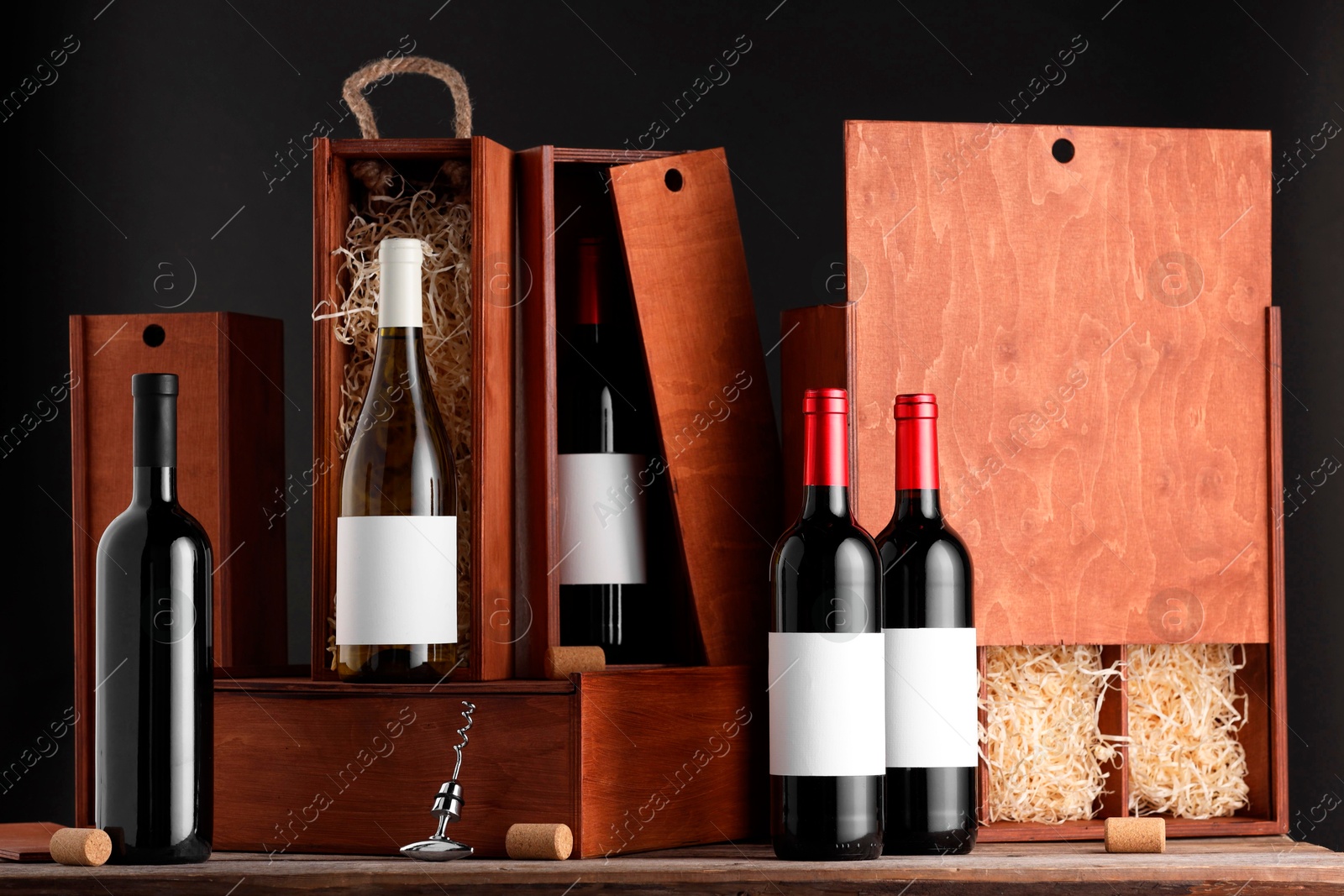 Photo of Different bottles of wine, wooden boxes, corks and corkscrew on table
