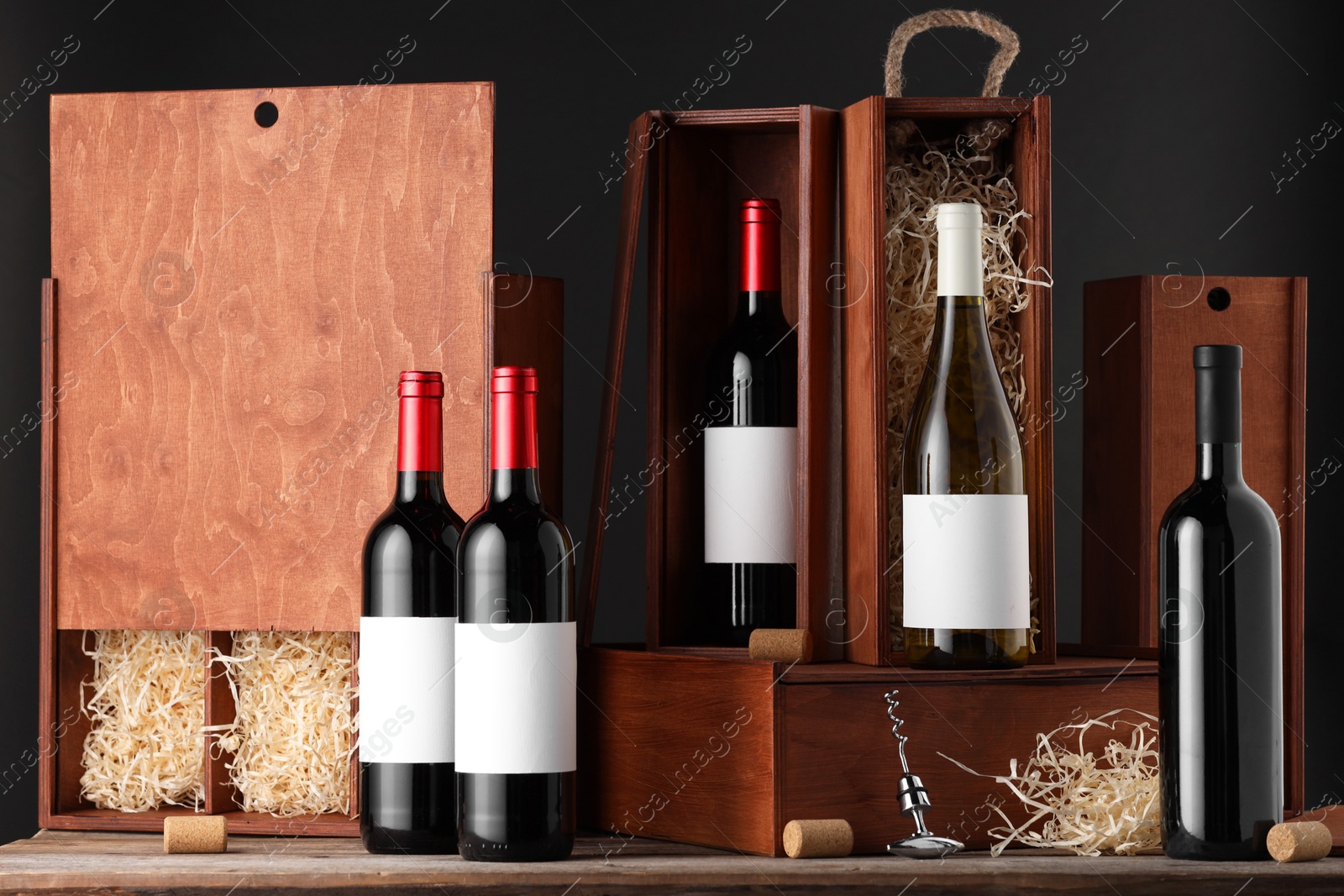 Photo of Different bottles of wine, wooden boxes, corks and corkscrew on table