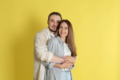 Happy couple hugging on yellow background. Strong relationship