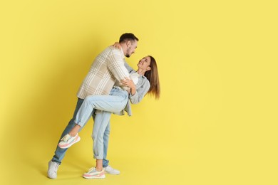 Photo of Happy couple dancing on yellow background. Space for text