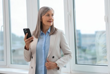 Photo of Senior woman using mobile phone at home, space for text