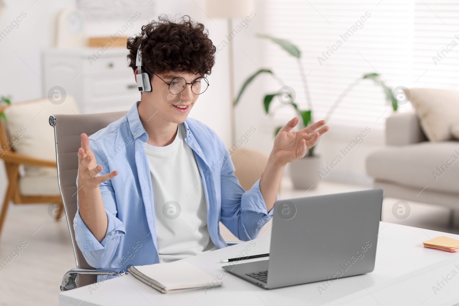 Photo of Teenager in headphones having video chat via laptop at home. Remote work