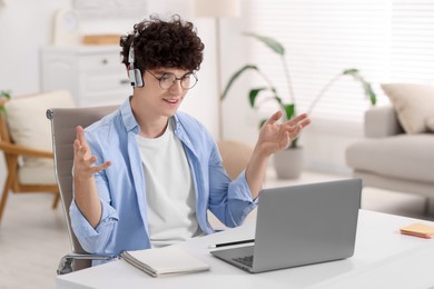 Teenager in headphones having video chat via laptop at home. Remote work