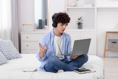 Teenager in headphones having video chat via laptop at home. Remote work