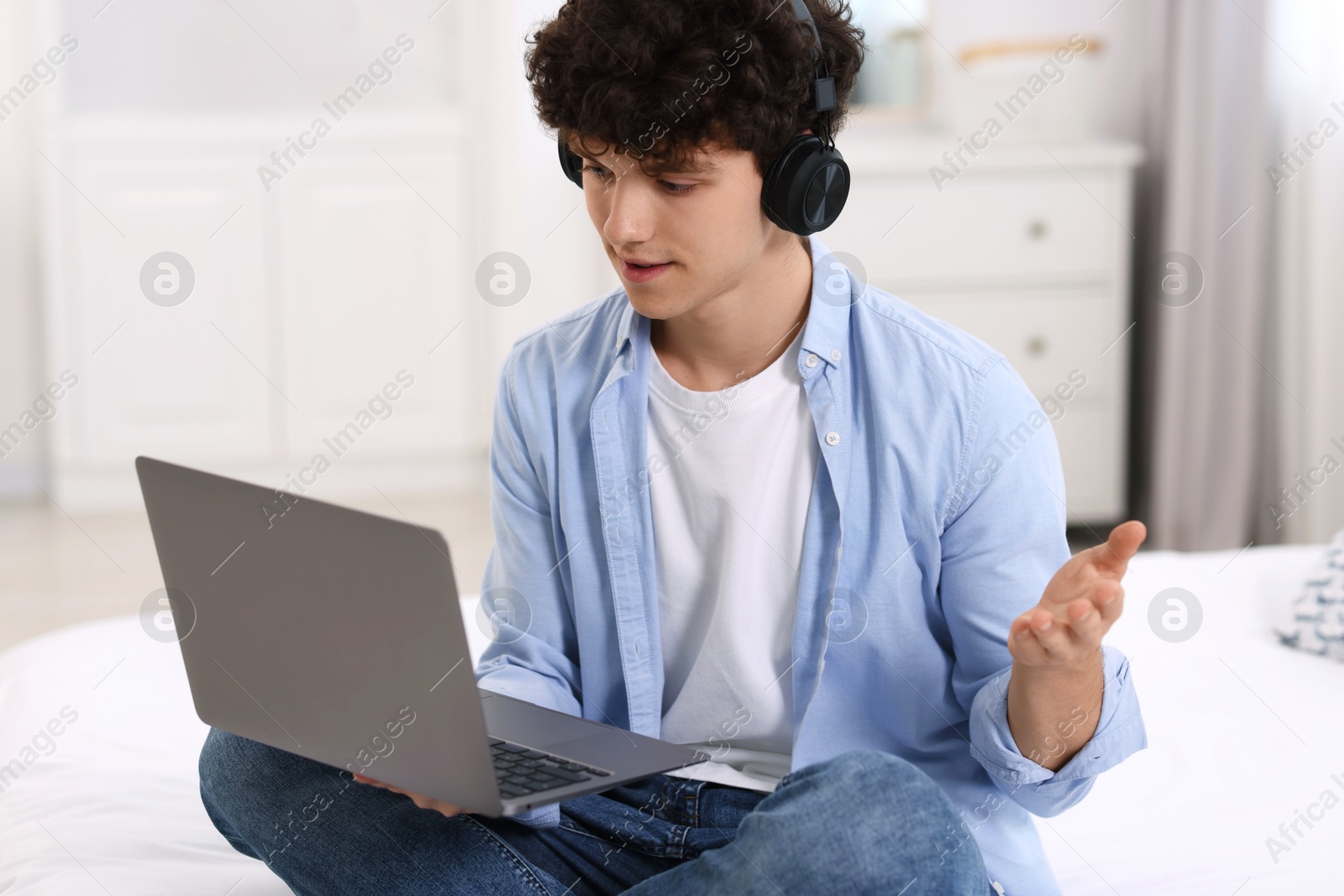 Photo of Teenager in headphones having video chat via laptop at home. Remote work