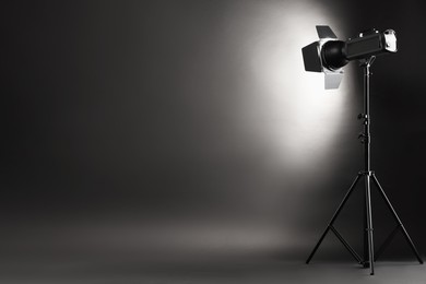 Photo of Dark photo background and professional lighting equipment in studio. Space for text