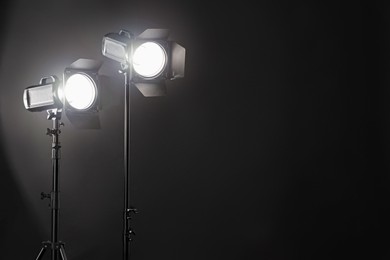 Photo of Dark photo background and professional lighting equipment in studio. Space for text