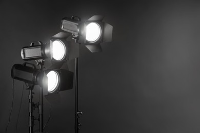 Dark photo background and professional lighting equipment in studio. Space for text