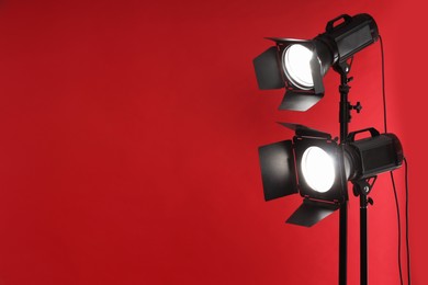 Red photo background and professional lighting equipment in studio, space for text