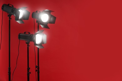 Red photo background and professional lighting equipment in studio, space for text