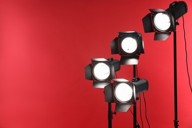 Red photo background and professional lighting equipment in studio, space for text