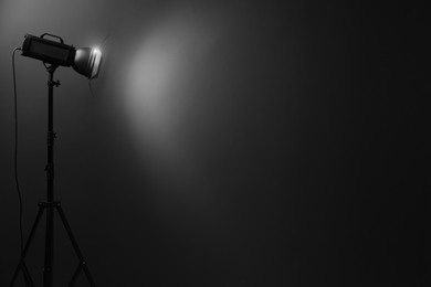Dark photo background and professional lighting equipment in studio, space for text