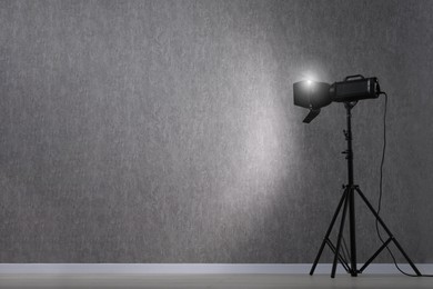 Grey photo background and professional lighting equipment in studio, space for text