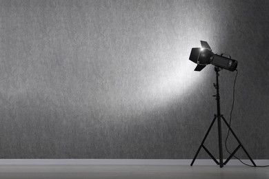 Grey photo background and professional lighting equipment in studio, space for text