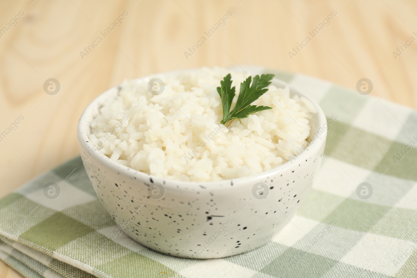 Photo of Delicious boiled rice in bowl and parsley on table, closeup