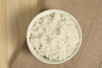 Photo of Delicious boiled rice in bowl on wooden table, top view