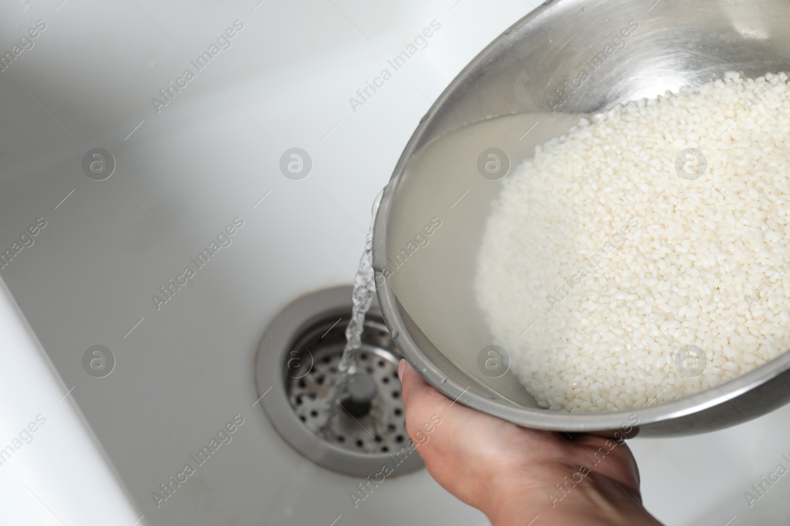 Photo of Woman rinsing rice in bowl above sink, closeup. Space for text