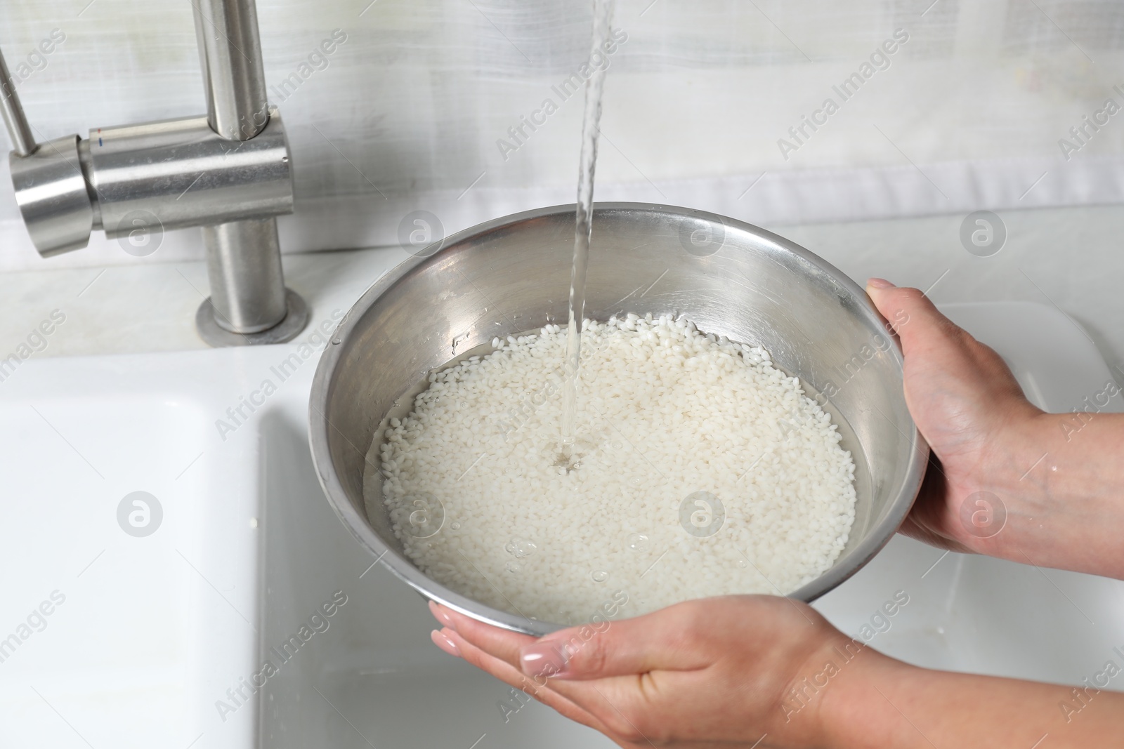 Photo of Woman rinsing rice in bowl above sink, closeup