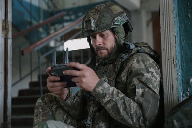 Military mission. Soldier in uniform with drone controller inside abandoned building