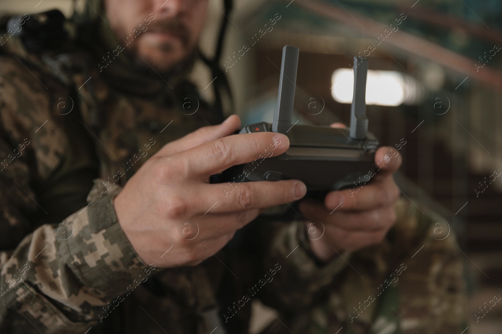 Photo of Military mission. Soldier in uniform with drone controller inside abandoned building, closeup