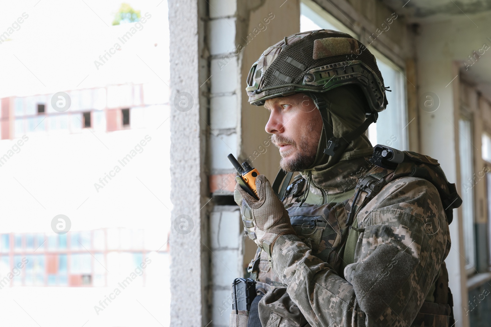 Photo of Military mission. Soldier in uniform with radio transmitter inside abandoned building, space for text
