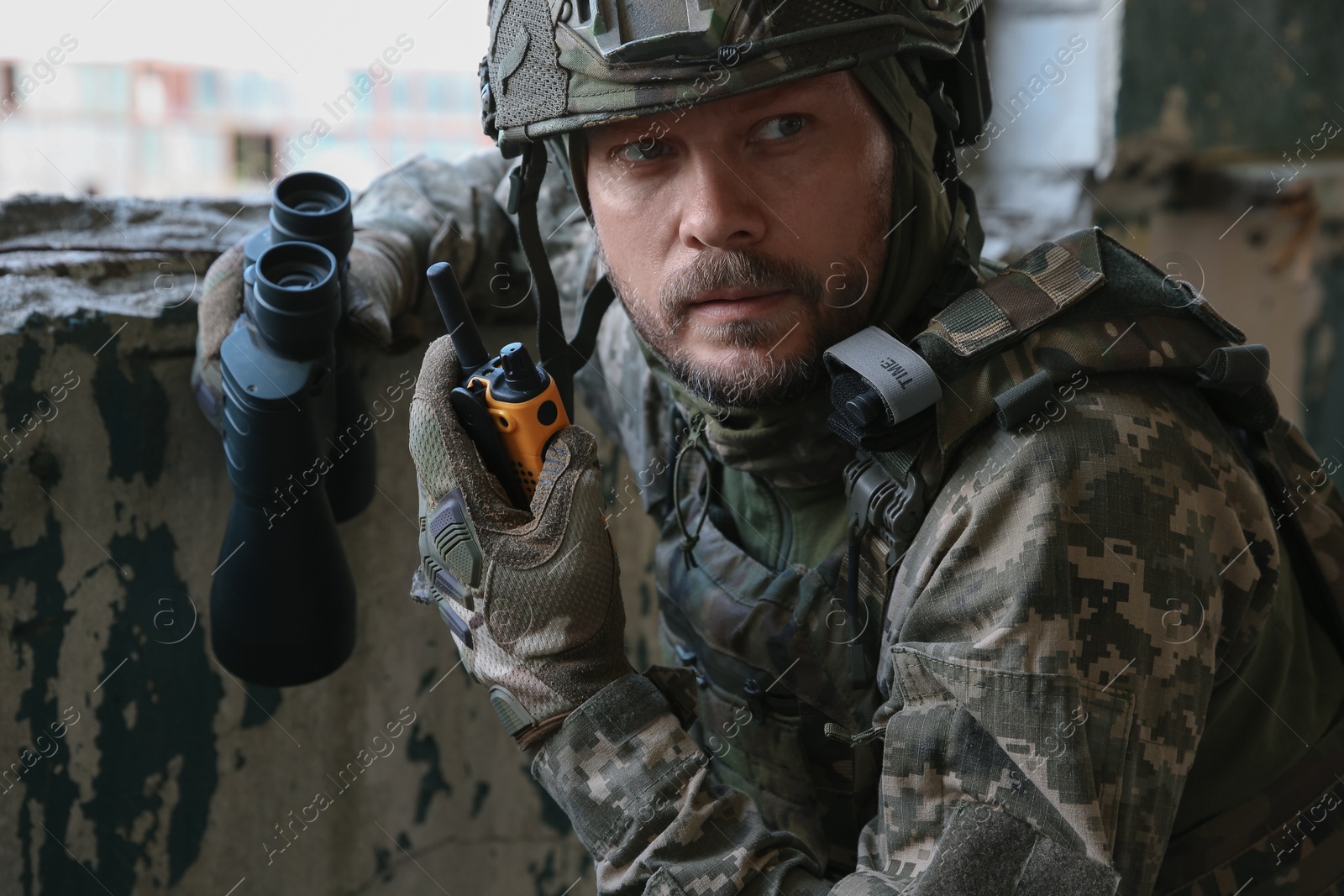 Photo of Military mission. Soldier in uniform with binoculars inside abandoned building