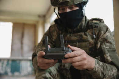 Photo of Military mission. Soldier in uniform with drone controller inside abandoned building, selective focus