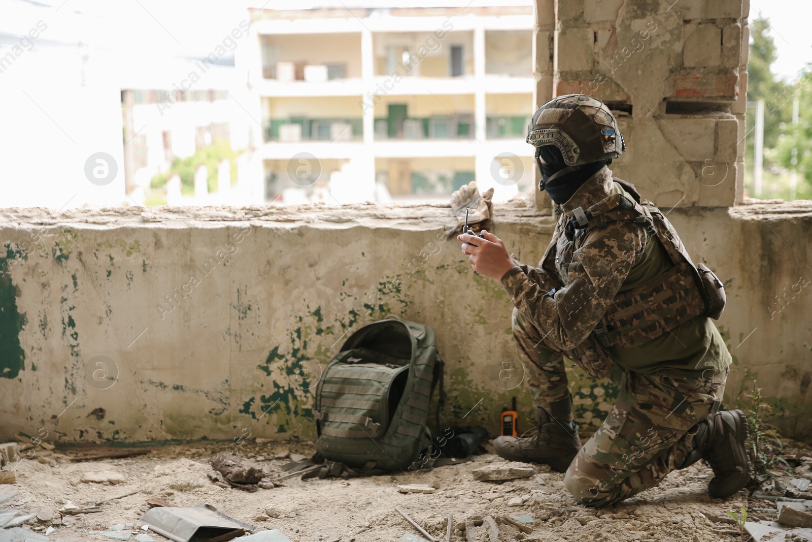 Photo of Military mission. Soldier in uniform with drone controller inside abandoned building, space for text