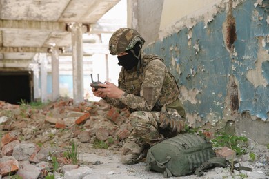 Photo of Military mission. Soldier in uniform with drone controller inside abandoned building