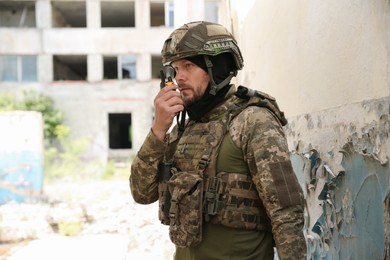 Military mission. Soldier in uniform radio transmitter near abandoned building outdoors