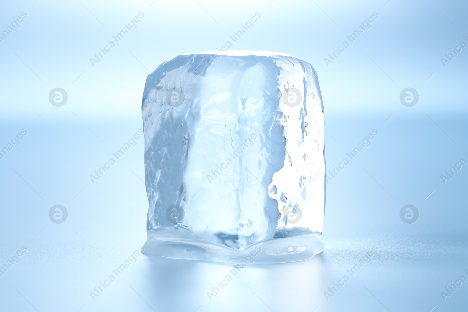 Photo of Cube of clear ice on light blue background