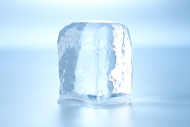 Cube of clear ice on light blue background