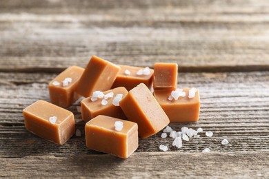 Photo of Yummy caramel candies with sea salt on wooden table, closeup