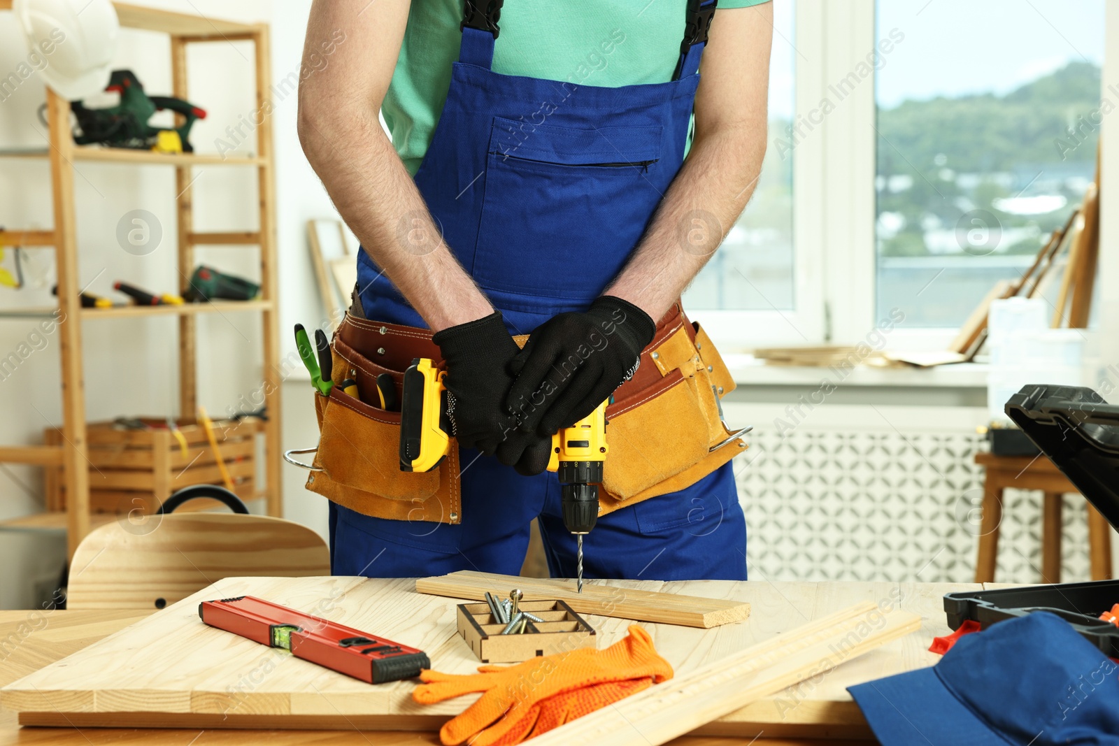 Photo of Craftsman working with drill at table in workshop, closeup